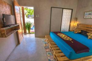 sypialnia z niebieskim łóżkiem i telewizorem w obiekcie Surfer Garden w mieście Sanur