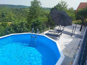 una piscina azul con una escalera y una sombrilla en Kuća za odmor Prinčeva oaza, en Molvice