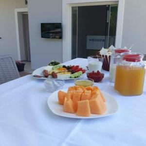 a white table with a plate of fruit and a drink at Vila Ervin Ksamil in Ksamil