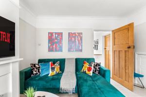 una sala de estar con un sofá verde con almohadas en Stunning Norwich Gem Sleeps 7 - Parking - Garden en Earlham