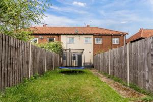 a backyard with a fence and a blue trampoline at Beautiful Norwich Gem Sleeps 7 - Parking - Garden in Earlham