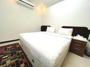 Al Taraf Hotel Apartment في صور: غرفة نوم بسرير كبير مع شراشف بيضاء