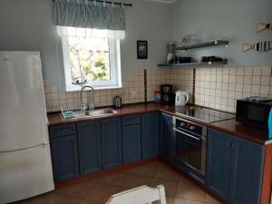 a kitchen with blue cabinets and a sink and a window at Całoroczny dom Morska Laguna in Kopalino