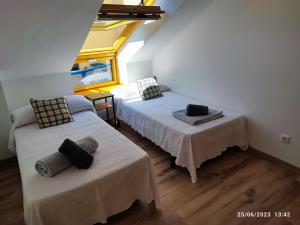 a attic room with two beds and a window at Mondariz Donde el Agua es Vida in Mondariz