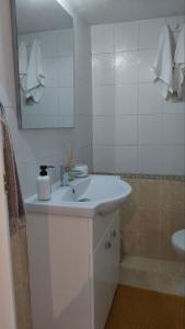 Baño blanco con lavabo y espejo en LENIA, en Nea Plagia