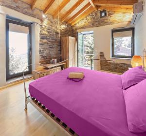ein großes lila Bett in einem Zimmer mit Fenstern in der Unterkunft Ikaria View Resort and Villa with Pool in Arethousa