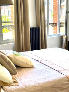 a bed with two pillows in a room with windows at Confortable 2 pièces au cœur de dreux #2 in Dreux