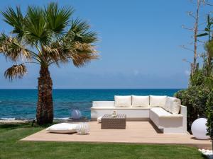 un sofá blanco sentado en una terraza cerca del océano en Hersonissos Beach Villa en Hersonissos
