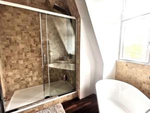 La salle de bains est pourvue d'une douche avec une porte en verre. dans l'établissement Grand appartement dans Château Néo-gothique, à Orléans