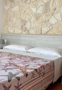 a bed in a room with a stone wall at VILLA MARIA ELENA Charme B&B in Capo Vaticano