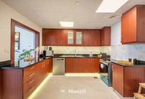 a large kitchen with wooden cabinets and a sink at Manzil - Lavish 3BR in JBR with Sea Views and 5 min walk to beach in Dubai