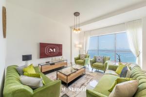 a living room with green furniture and a large window at Manzil - Lavish 3BR in JBR with Sea Views and 5 min walk to beach in Dubai