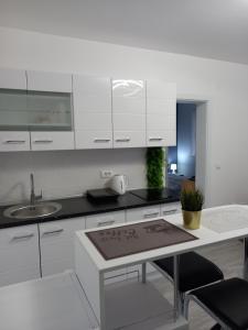 cocina con armarios blancos, fregadero y mesa en Silver Lake Apartments, en Veliko Gradiste