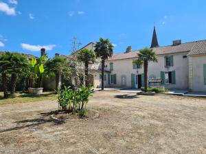 una casa con palmeras delante en L'hacienda de Soubran, Le Gîte à Grand-mère, classé 4 étoiles, en Soubran