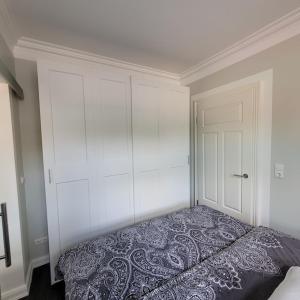 Dormitorio blanco con cama y armario en Ferienwohnung Abendsonne en Zarrentin