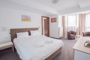 una habitación de hotel con una cama grande y una silla en Acomodoro Residence, en Bucarest