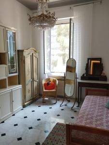 a bedroom with a chandelier and a chair and a window at Casa Nonna Anna in Genova