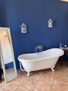 eine weiße Badewanne in einem blauen Bad mit einem Spiegel in der Unterkunft The Tower Of The Old King in Desenzano del Garda
