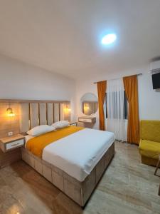 a bedroom with a large bed and a yellow chair at Apartmani Enydoo in Ulcinj