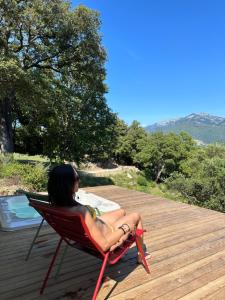 a woman sitting in a chair next to a pool at Maison d'Hôtes Zella in Bains de Guitera