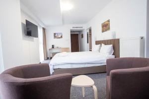 a hotel room with a bed and two chairs at Acomodoro Residence in Bucharest