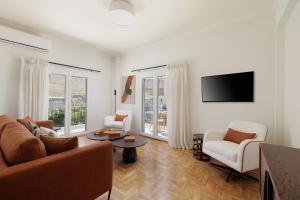 a living room with a couch and chairs and a tv at Vanda's Maison in Corfu Town