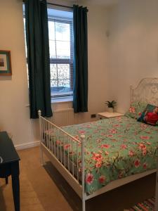 a bedroom with a bed with a green comforter and a window at 2 Double Rooms-Sleeps 4- 2 Bathrooms in Rossendale