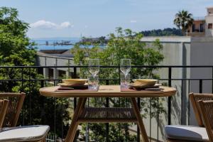 a table with glasses and plates on a balcony at Vanda's Maison in Corfu Town