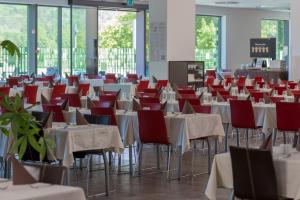 a room full of tables and chairs with red chairs at Rimske Terme Resort - Hotel Rimski dvor in Rimske Toplice