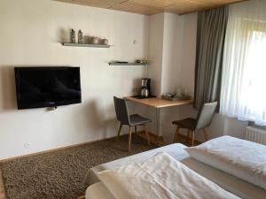 ein Hotelzimmer mit einem Bett, einem Schreibtisch und einem TV in der Unterkunft Zani Helga in Schruns-Tschagguns