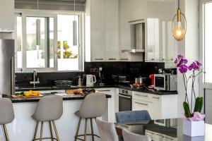 een keuken met witte kasten en barkrukken bij Fig Tree Bay Residences 6 in Protaras