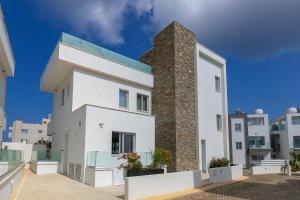 a white house with a brick chimney at Fig Tree Bay Residences 6 in Protaras