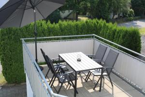 einen Tisch und Stühle auf einem Balkon mit Sonnenschirm in der Unterkunft Moderne Ferienwohnung im Allgäu in Erkheim