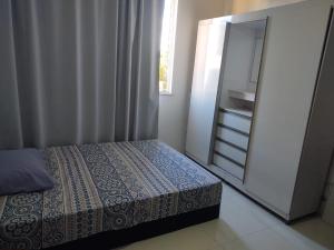 Dormitorio pequeño con cama y espejo en Pituba quartos, en Salvador