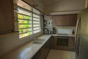 a kitchen with wooden cabinets and a large window at Ocean front villa, pool, private ocean snorkeling in Simpson Bay