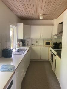 Il comprend une cuisine avec des placards blancs et un plafond en bois. dans l'établissement Skibstedborg - naturhytte i Thy, à Sønder Ydby