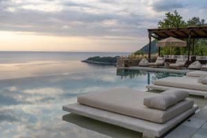 a swimming pool with lounge chairs and the ocean at Agapitos Villas & Guesthouses in Agios Ioannis Pelio