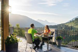 a man and woman sitting at a table on a balcony at Alpenhotel Wanderniki in Liesing