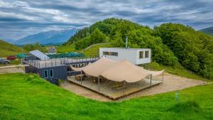 a building with a tent in the middle of a field at Ursa Mica Glamping Resort in Şirnea