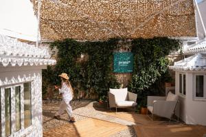 a woman walking in front of a ivy covered building at Praia FLH Hotels Ericeira in Ericeira