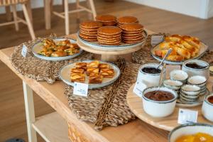 a table with plates of food and pancakes and pastries at Praia FLH Hotels Ericeira in Ericeira