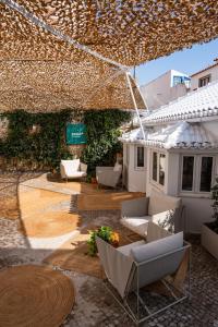 a patio with couches and chairs under a tent at Praia FLH Hotels Ericeira in Ericeira