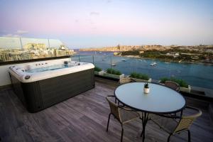 a bathroom with a bath tub and a table and a view at The Londoner Hotel Sliema in Sliema