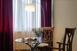 a glass table with a vase of flowers and a plate of food at Hotel Aisi in Batumi