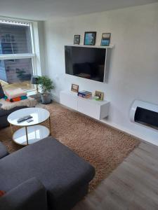 een woonkamer met een bank en een tv aan de muur bij Tæbring Holiday Home in Nykøbing Mors
