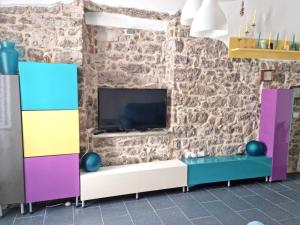een woonkamer met een tv aan een bakstenen muur bij One bedroom appartement at Calasetta 650 m away from the beach with enclosed garden and wifi in Calasetta