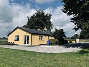 una pequeña casa amarilla en un camino de entrada en Cutteen Cottage, en Tulla