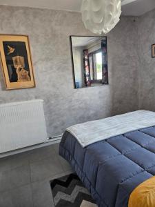 une chambre avec un lit bleu et un miroir dans l'établissement Appartement de charme , Royan, proche mer avec balcon., à Royan