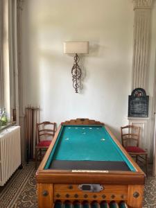 una mesa de billar en una habitación con sillas y una lámpara en B&B Le Manoir de la Douve, en Heuvelland