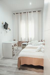 a white bedroom with a bed and a desk at Hostal Ruta de Francia in Barcelona
